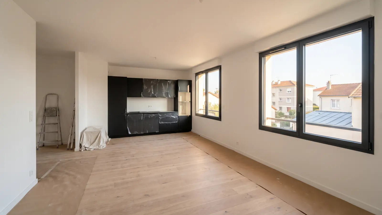 Séjour en fin de rénovation complète : parquet protégé, cuisine neuve encore sous film (image d’illustration)